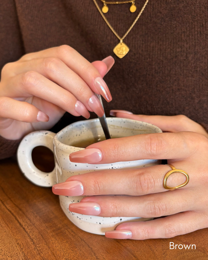 set de uñas press-on efecto glazed/aurora babyboomer en color marrón removiendo una taza de café