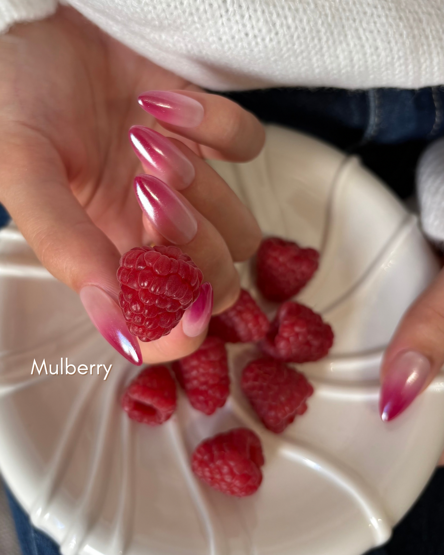 set de uñas press-on efecto glazed/aurora babyboomer en color  rosa muberry cogiendo una frambuesa con la mano