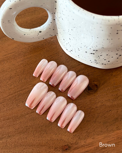 set de uñas press-on efecto glazed/aurora babyboomer en color marrón con fondo de taza de café