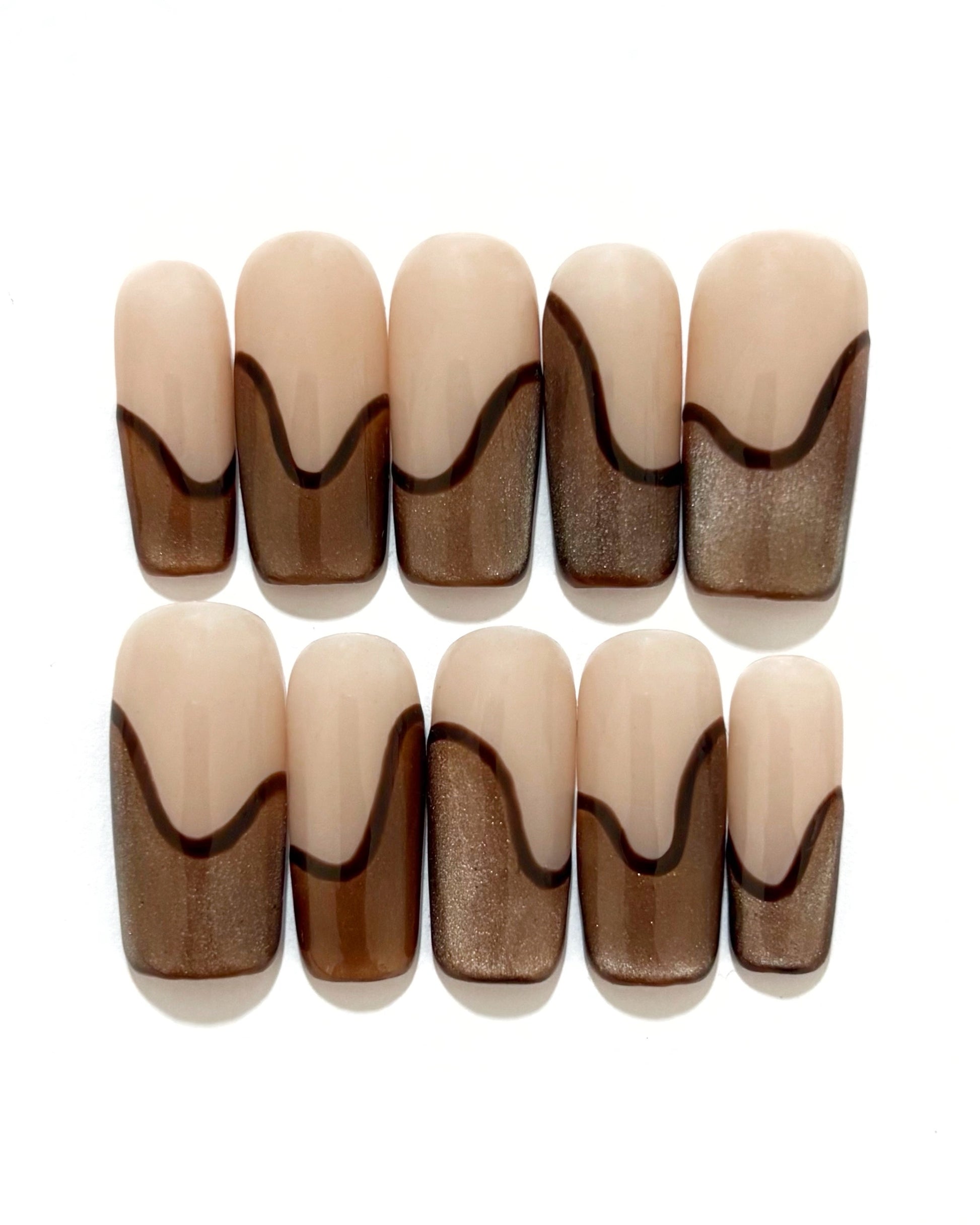 set de uñas press-on nude con francesa abstracta de color marrón con efecto ojo de gato y un línea delgada marrón que separa la francesa