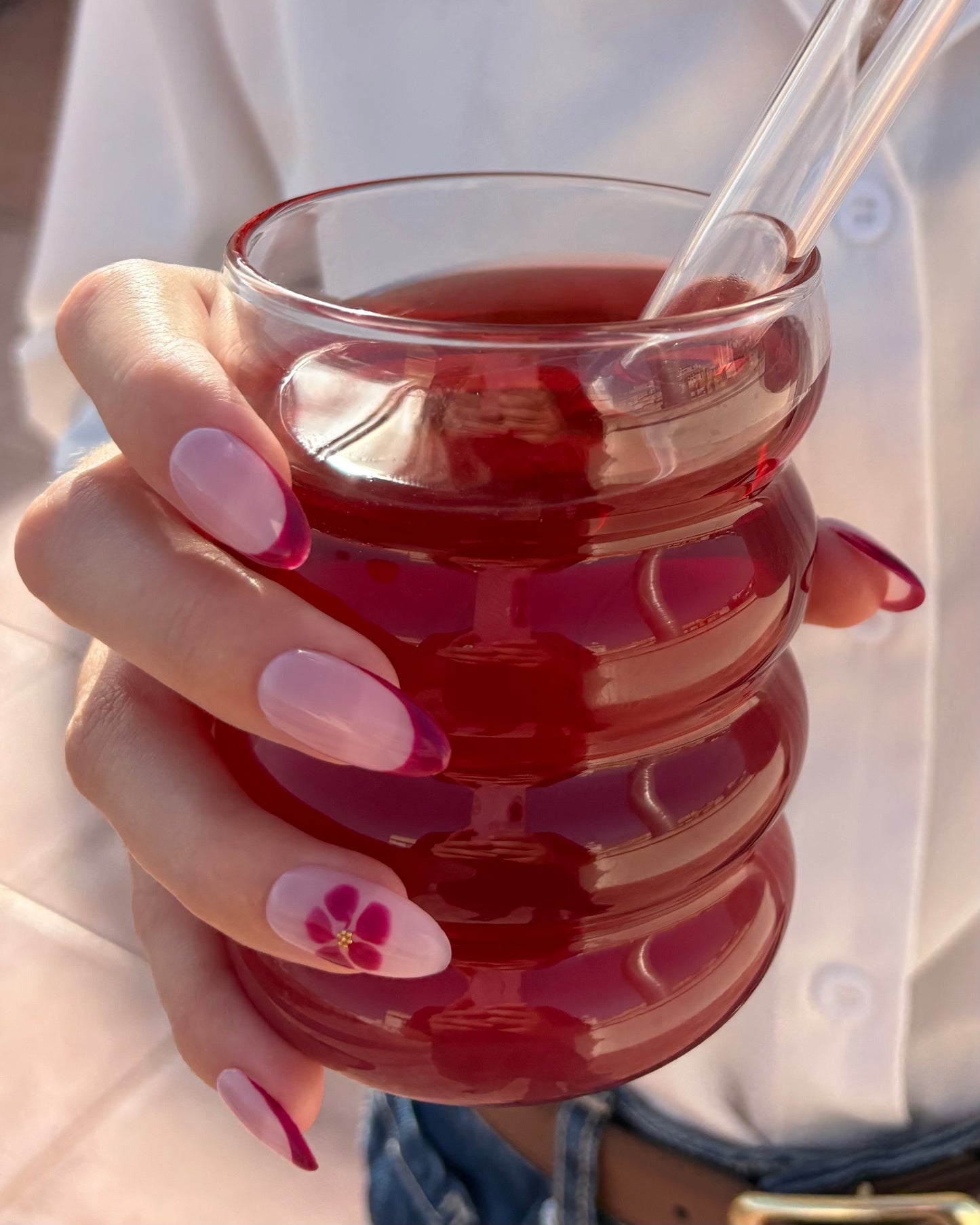 set de uñas press-on nudes con francesa burdeos y flor blooming con caviar dorado agarrando con solo una mano un bubble tea