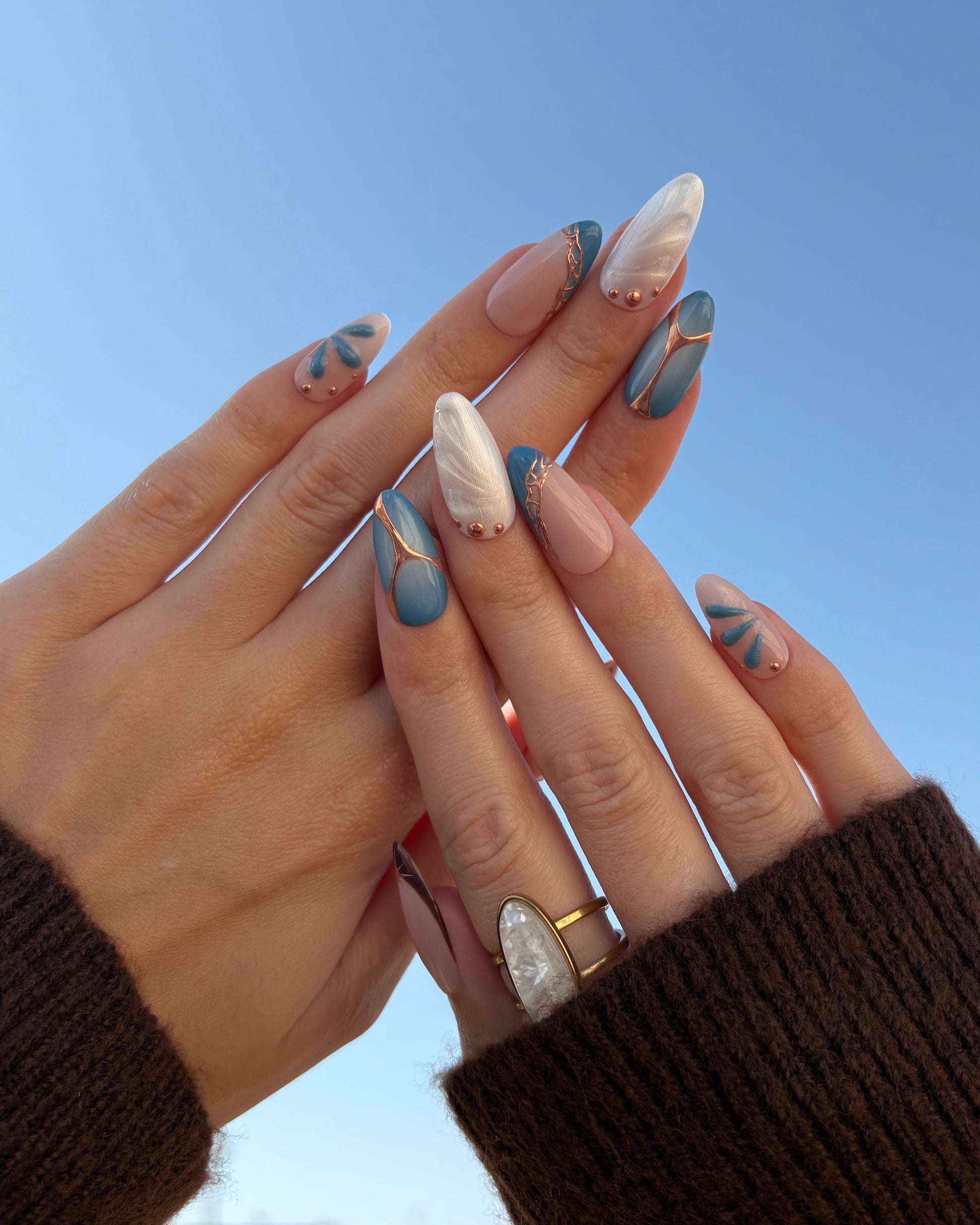 set de uñas press-on azul con toques de cobre cromático, degradado con aerógrafo, blanco perlado con gotas de gel 3D, ojo de gato y estrella 2 manos con fondo de cielo