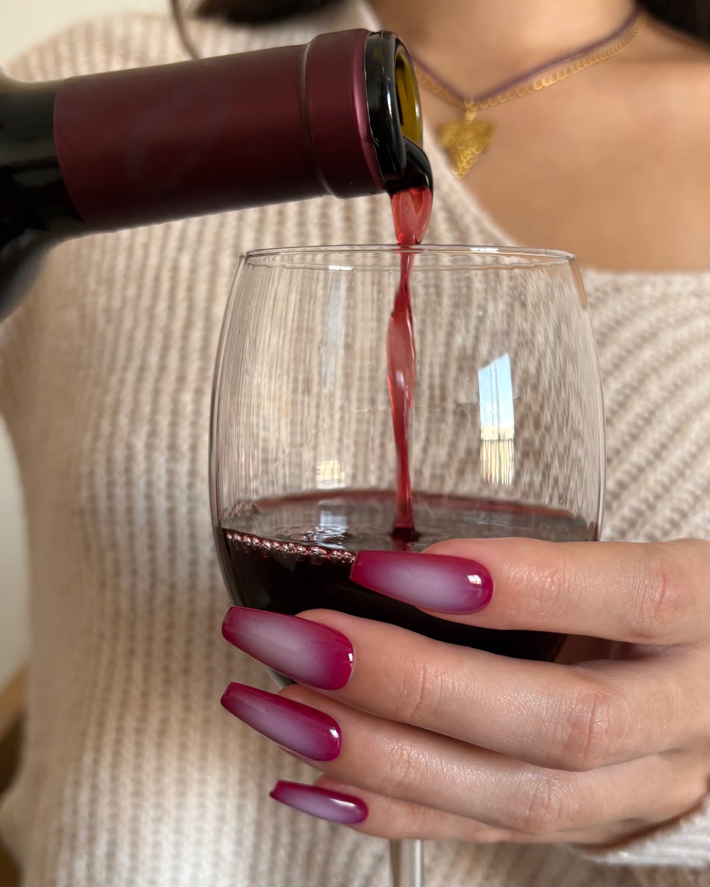 set de uñas press-on burdeos con degradado aura en el centro de color beige hecho con aerógrafo sirviendo una copa de vino