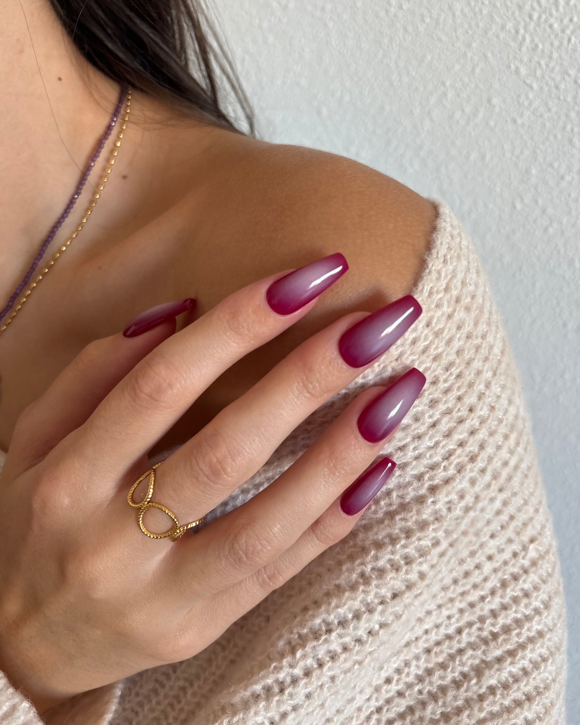 set de uñas press-on burdeos con degradado aura en el centro de color beige hecho con aerógrafo tocando hombro con anillo