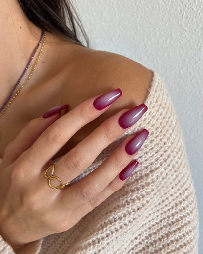 set de uñas press-on burdeos con degradado aura en el centro de color beige hecho con aerógrafo tocando hombro con anillo