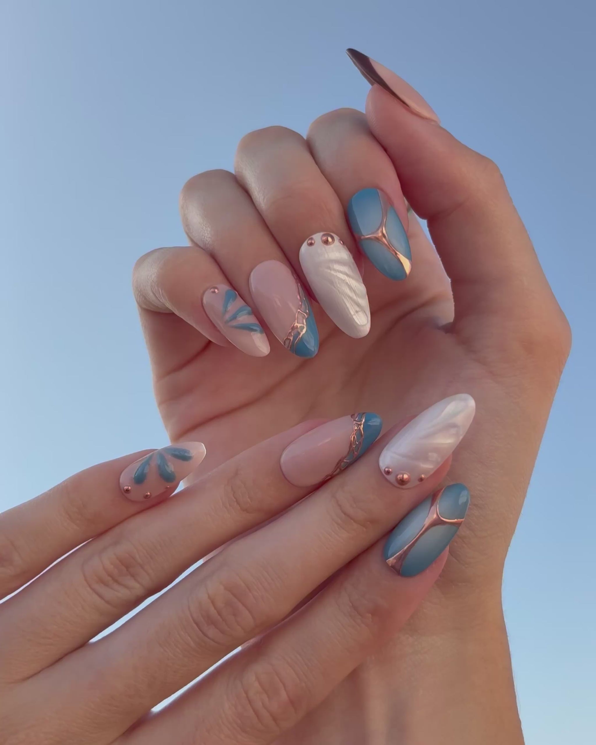 video de presentación set de uñas press-on azul con toques de cobre cromático, degradado con aerógrafo, blanco perlado con gotas de gel 3D, ojo de gato y estrella